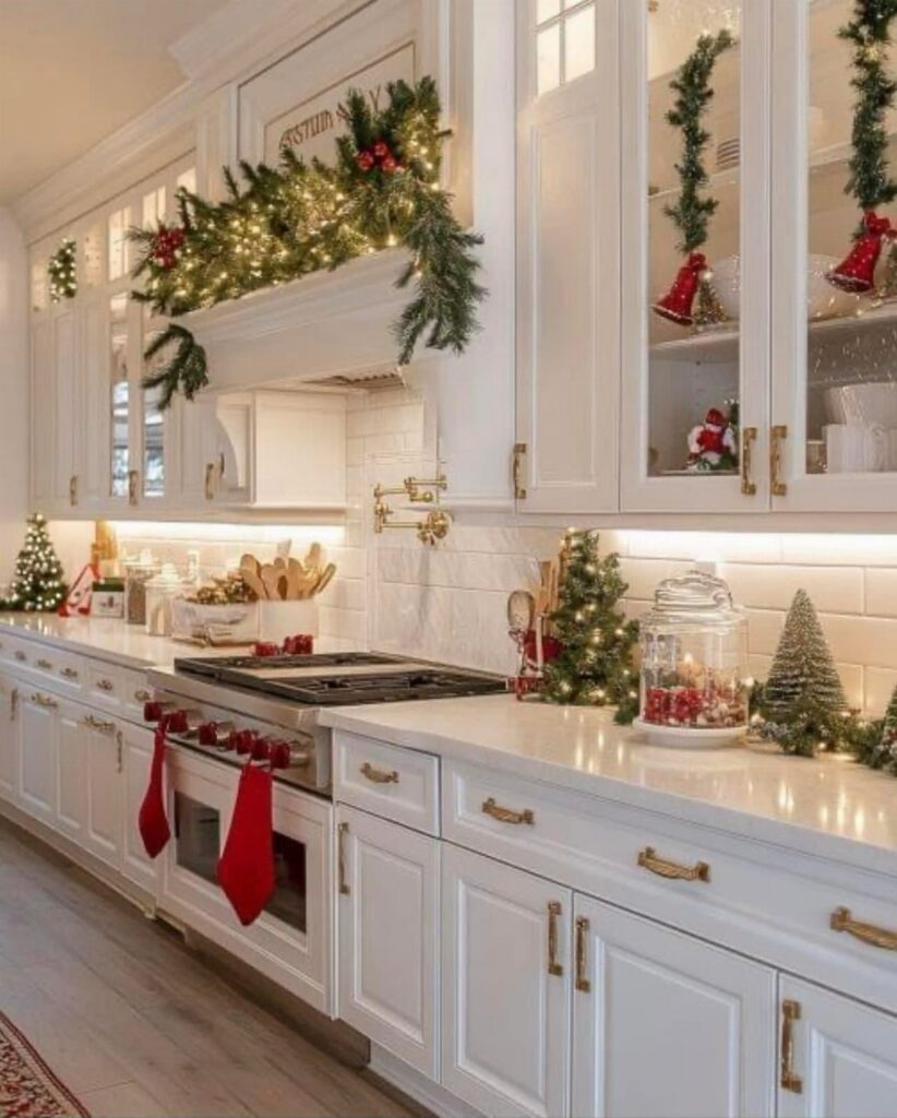 White kitchen counters decorated with small Christmas trees, garlands, and red stockings.