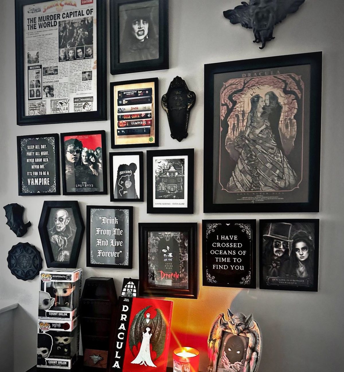 Framed gothic artwork and dark decorative pieces arranged in a gallery wall display.