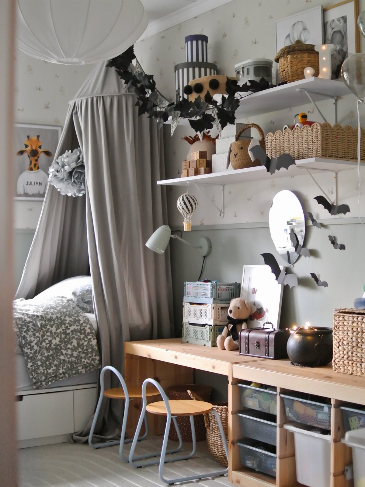 A child's bedroom decorated with black bat cutouts on walls and shelves.