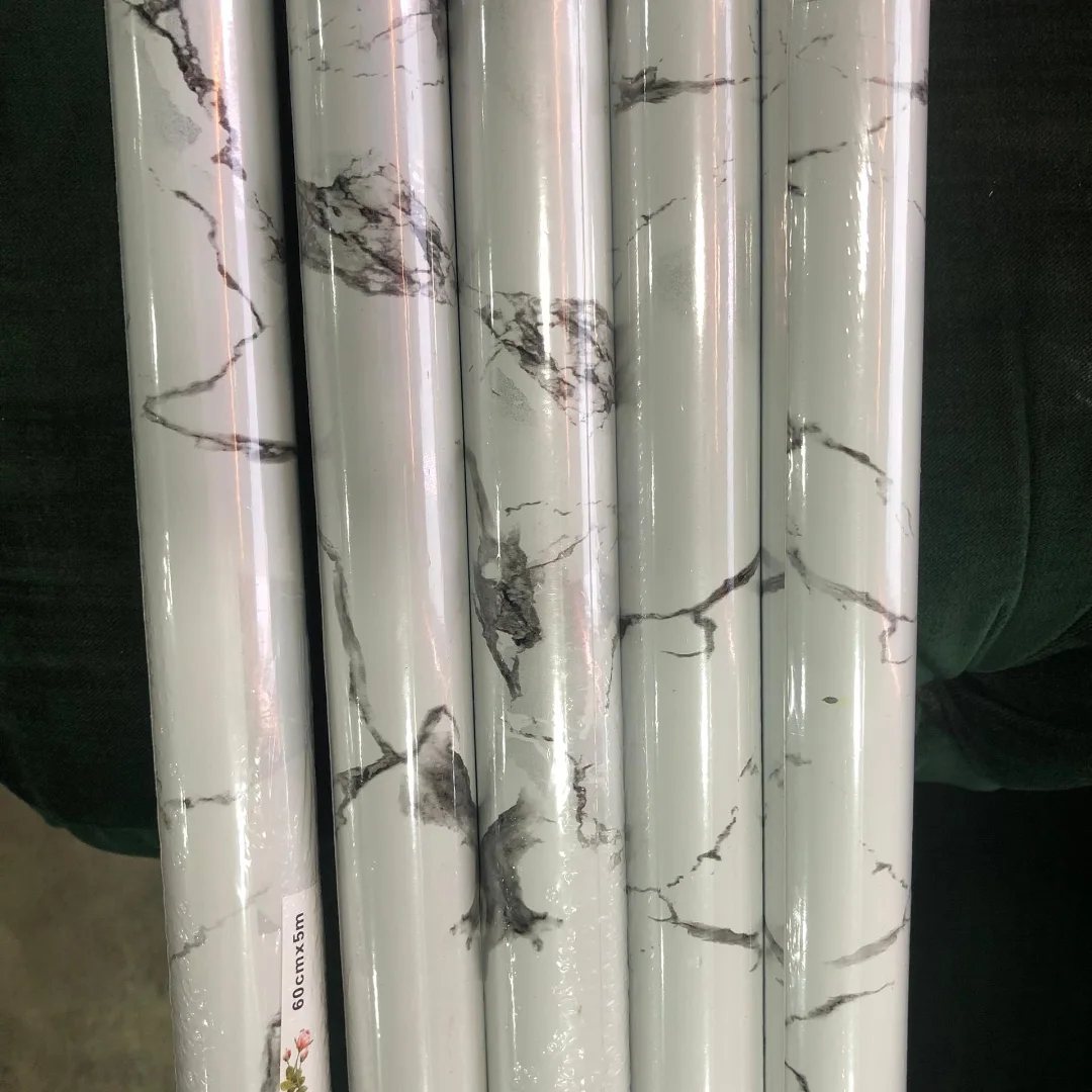 Five rolls of white and grey marble patterned wallpaper standing vertically side by side.