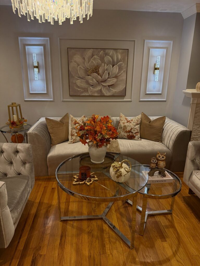 Modern living room with a grey sofa, glass coffee tables, and large floral wall art.