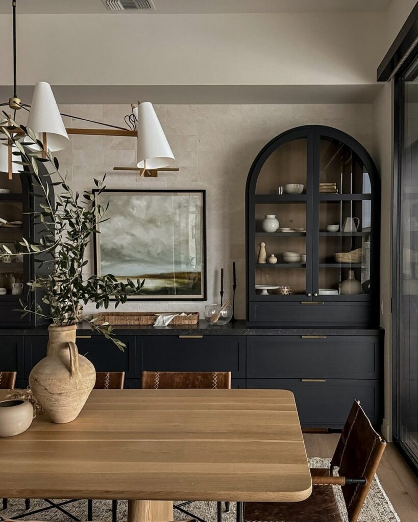 A wooden dining table with leather chairs set against dark navy cabinetry and neutral walls.