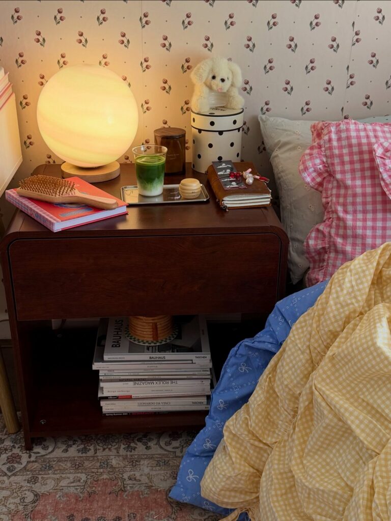Dark wood nightstand decorated with a glowing orb lamp, books, and a small stuffed animal.