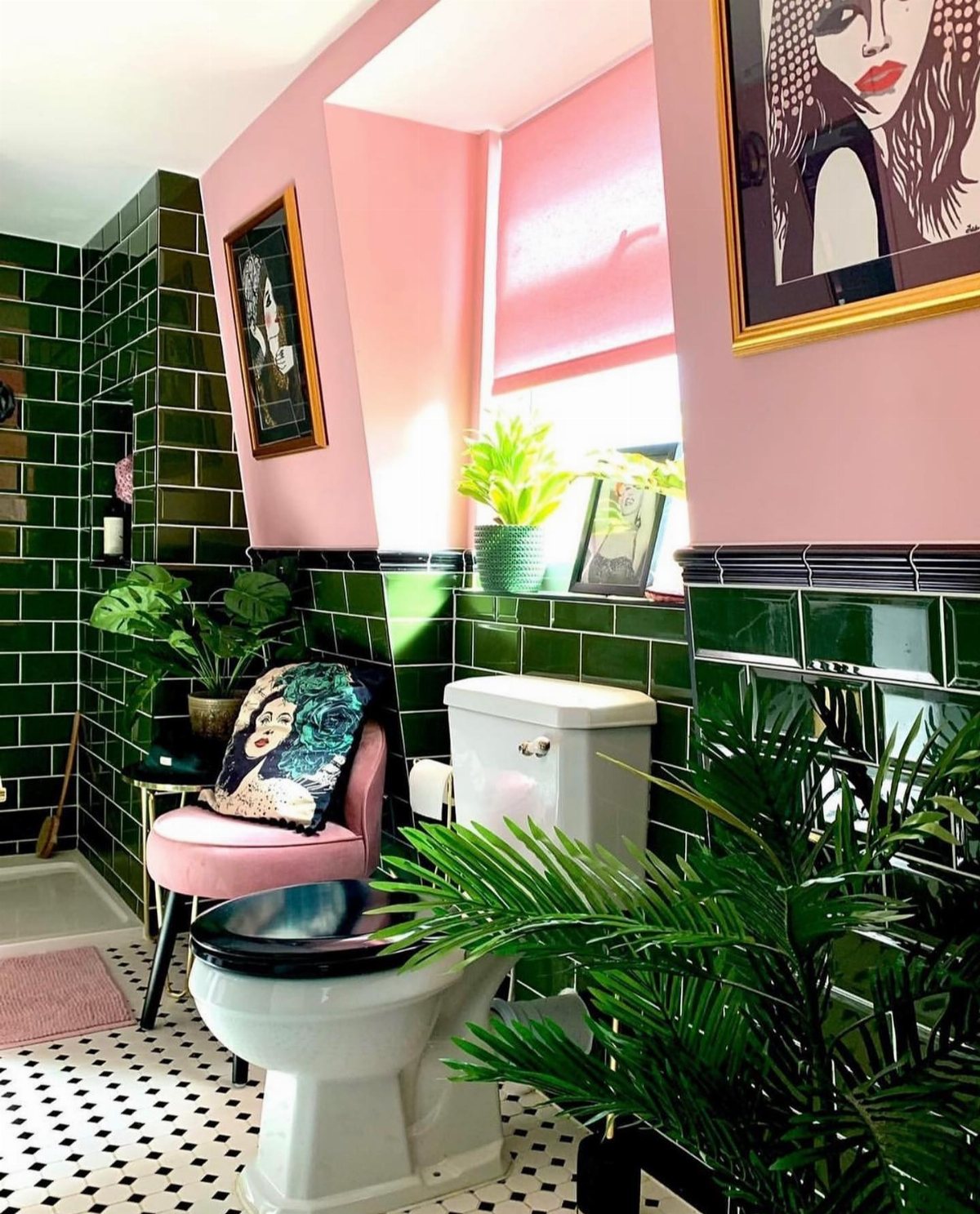Pink walls and green tiled bathroom with a white toilet and indoor plants.