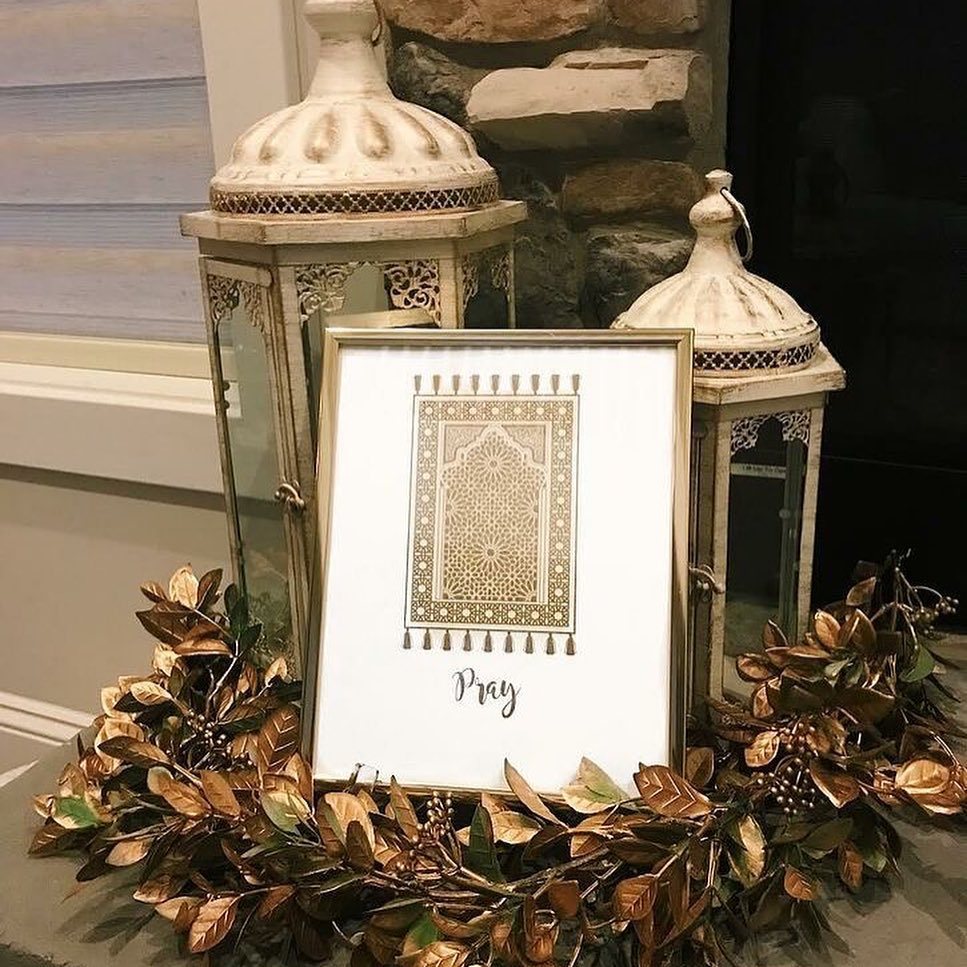 Decorative white lanterns and a framed 'Pray' print surrounded by metallic gold leaves.