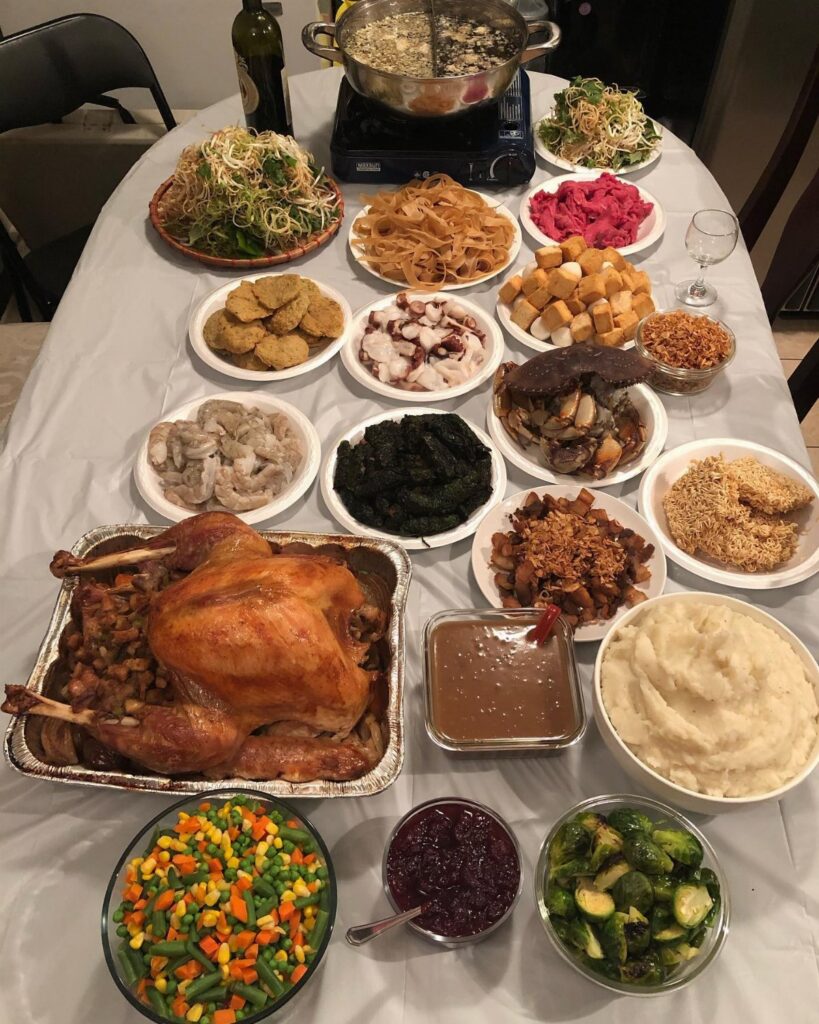 A large Thanksgiving feast featuring a roasted turkey, mashed potatoes, and various side dishes on a table.