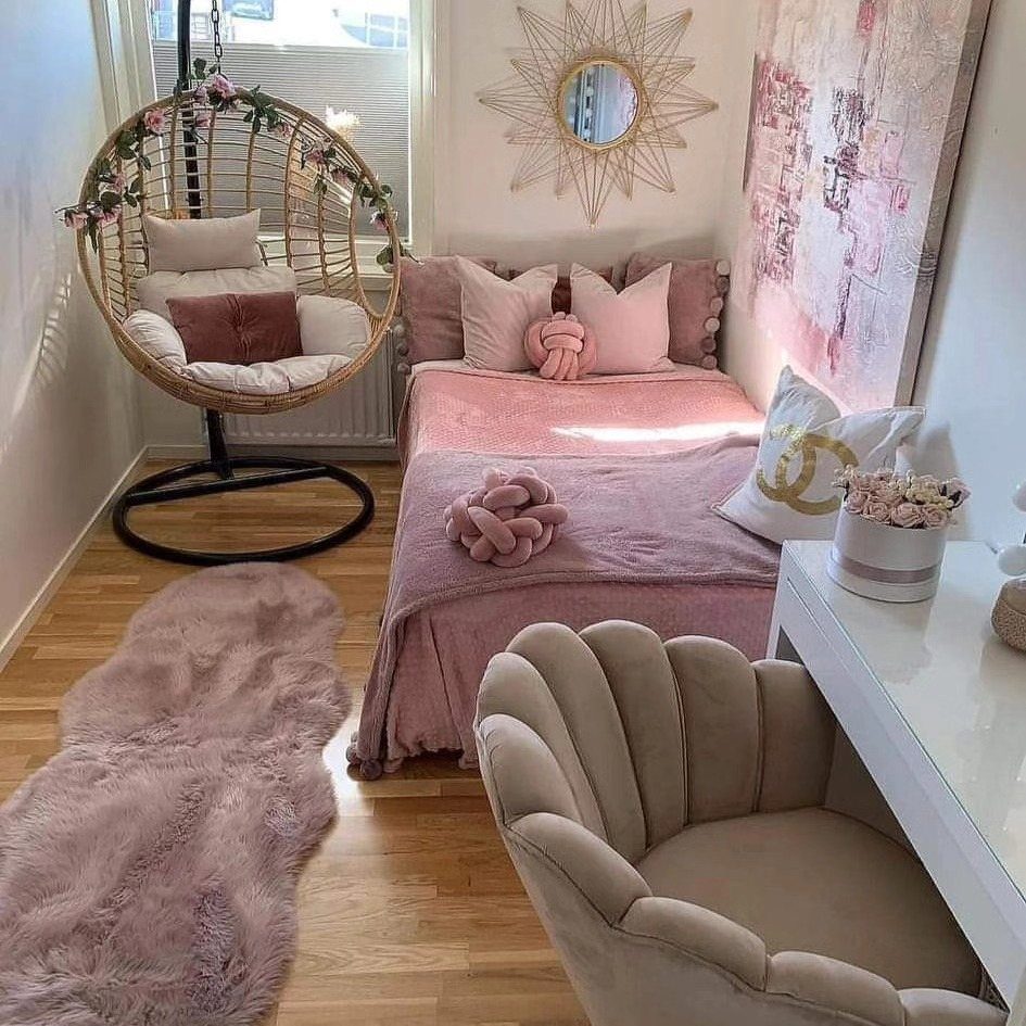 A small pink bedroom featuring a cozy bed, a hanging wicker chair, and a white desk.